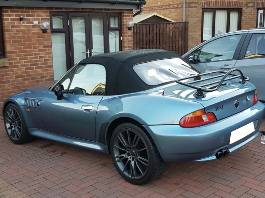blue bmw z3 with a luggage rack fitted on a paved drive outside a house