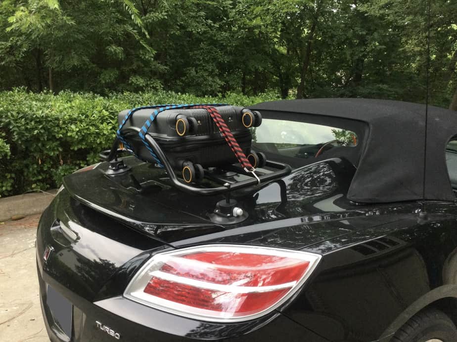 black saturn sky with a revo-rack luggage rack fitted carrying a suitcase next to a hedge