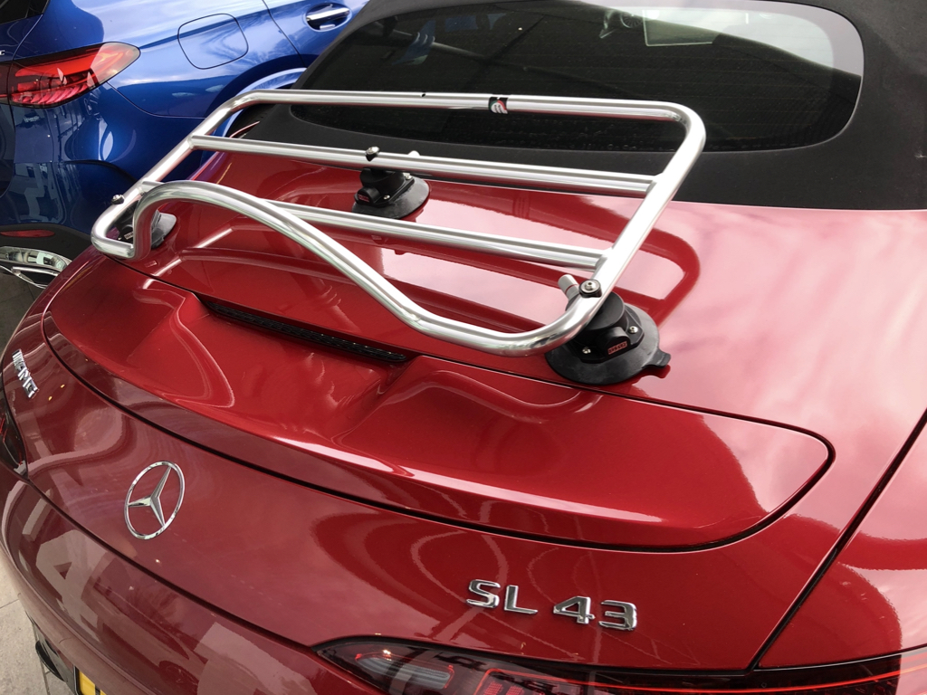 Red mercedes SL 43 AMG with a revo-rack luggage rack fitted photographed from the rear outside a mercedes showroom