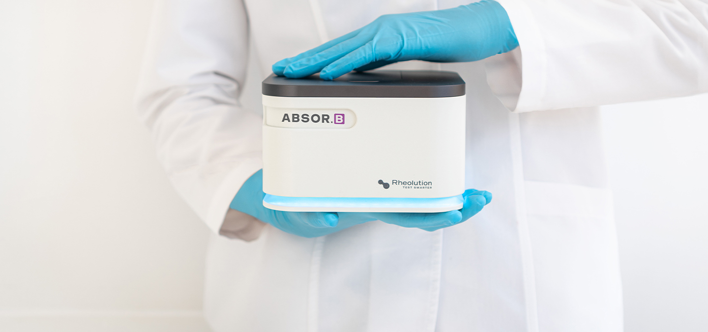 Person holding an ABSOR.B™, an Absorbance & Transmittance Meter, in their hand, demonstrating the device's size and usability.