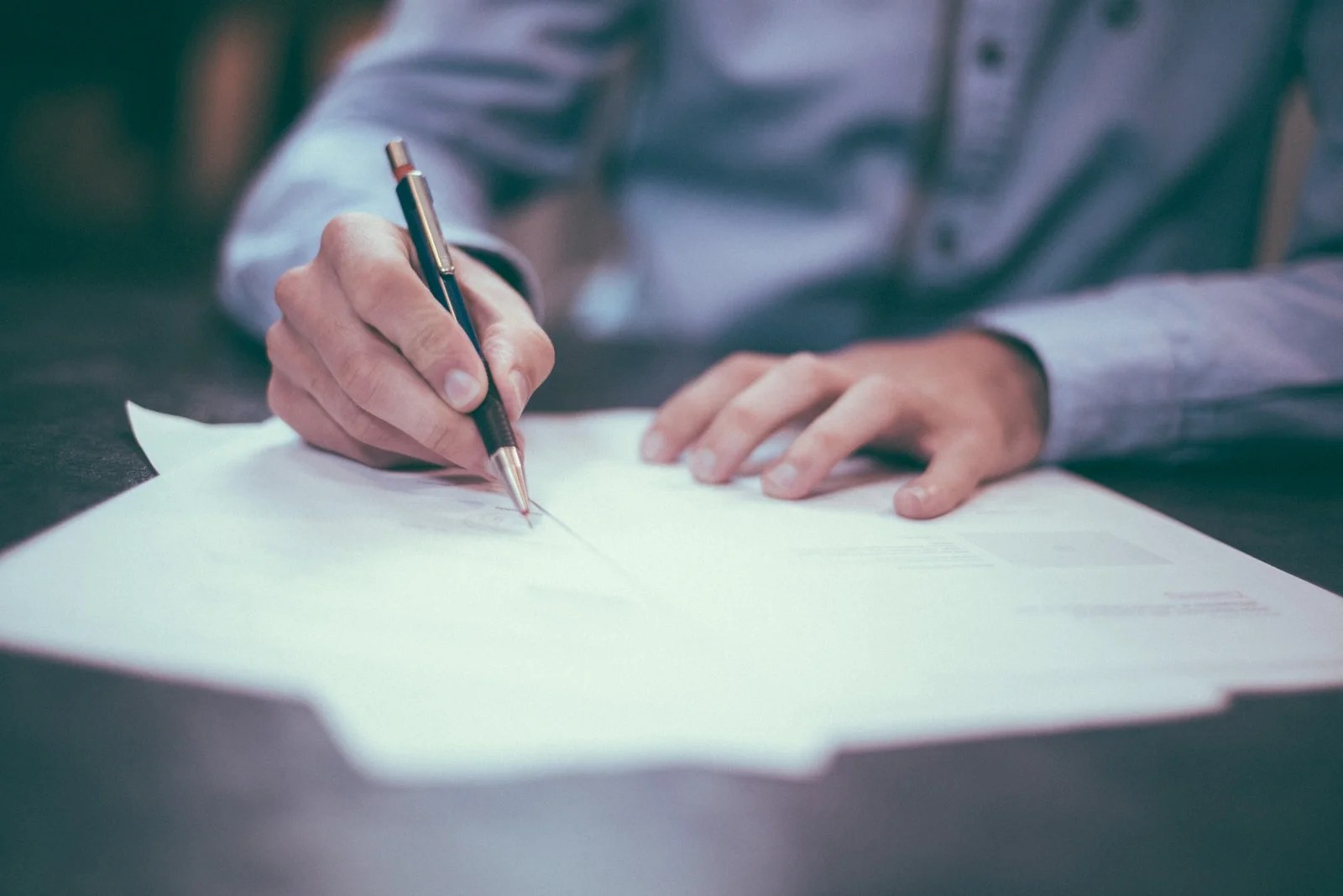 man in blue shirt writing on a piece of paper