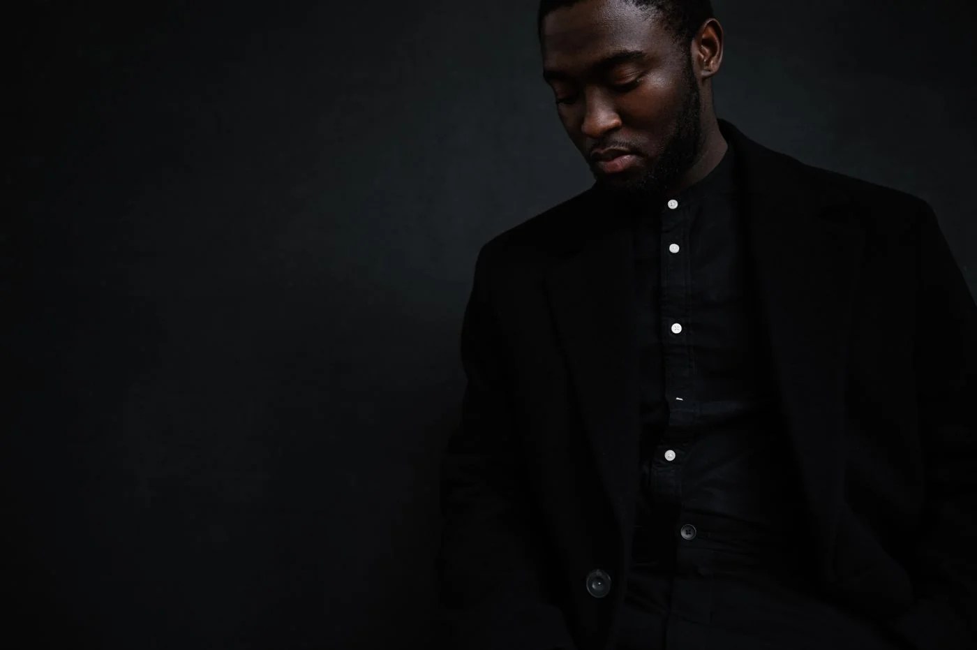 Black suit fashion portrait against a dark studio backdrop