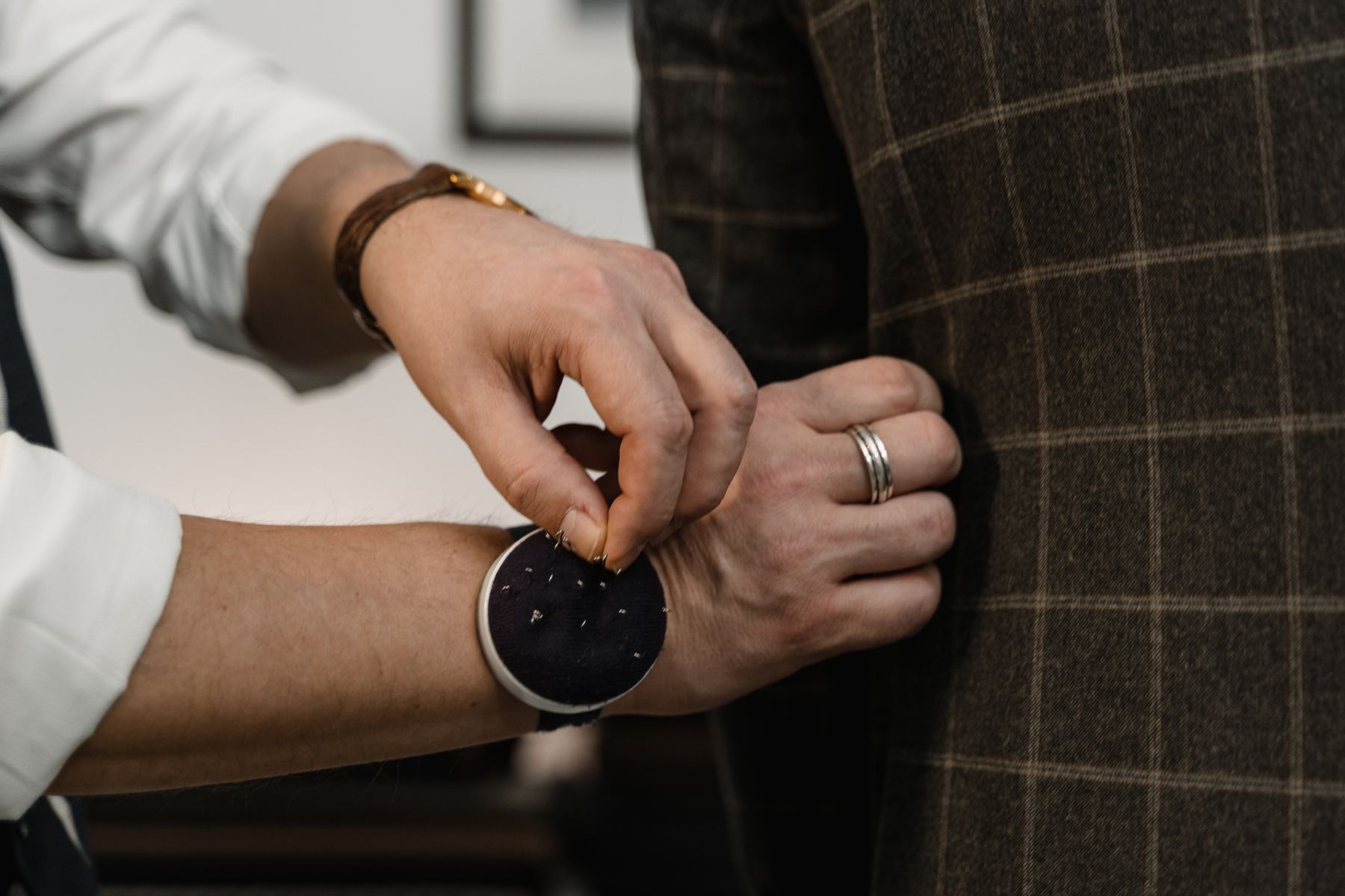 Tailor carefully adjusting a checked jacket in a fitting.