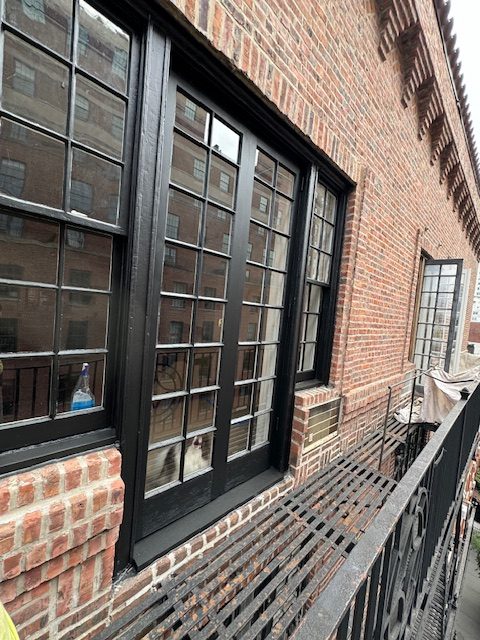 Exterior view of restored windows at 171 West 12th Street in Greenwich Village, showcasing black wood frames and multiple panes.