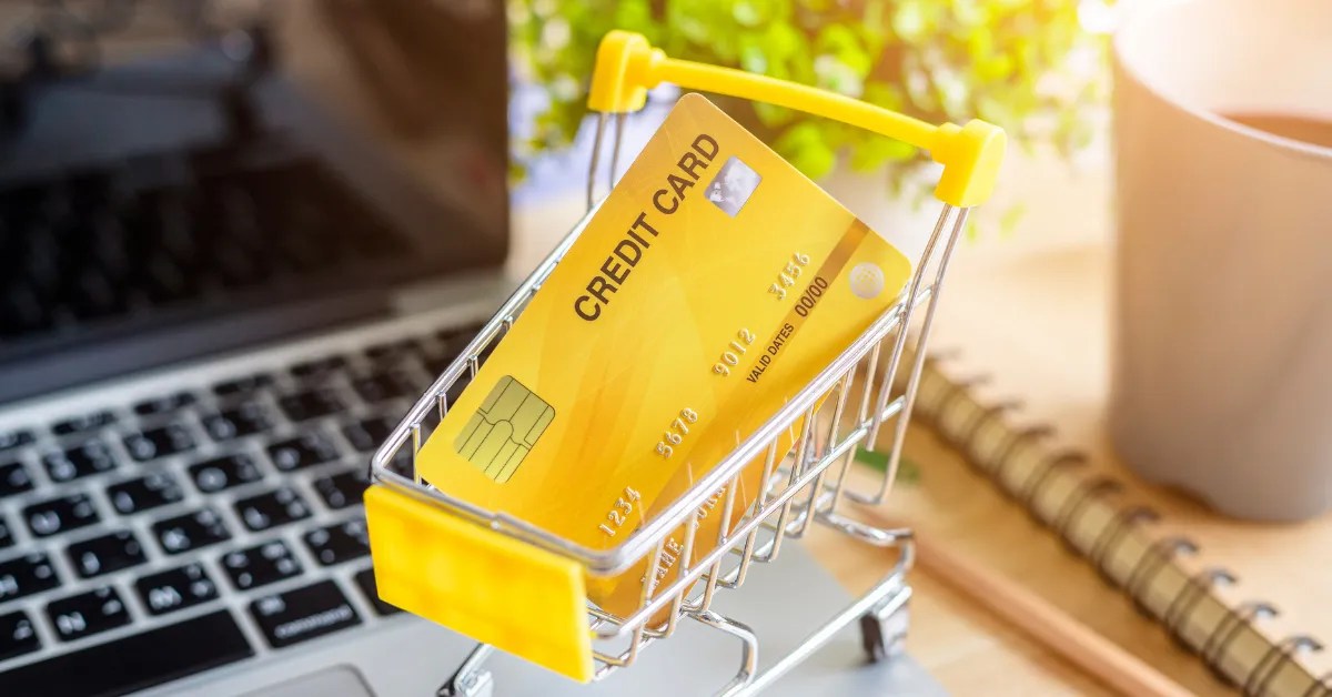 How to build credit Fast Boost Your Score RightWay in USA 4 How to Build Credit Fast - Yellow credit card in a miniature shopping cart on a laptop, representing financial growth and credit score improvement in the USA.
