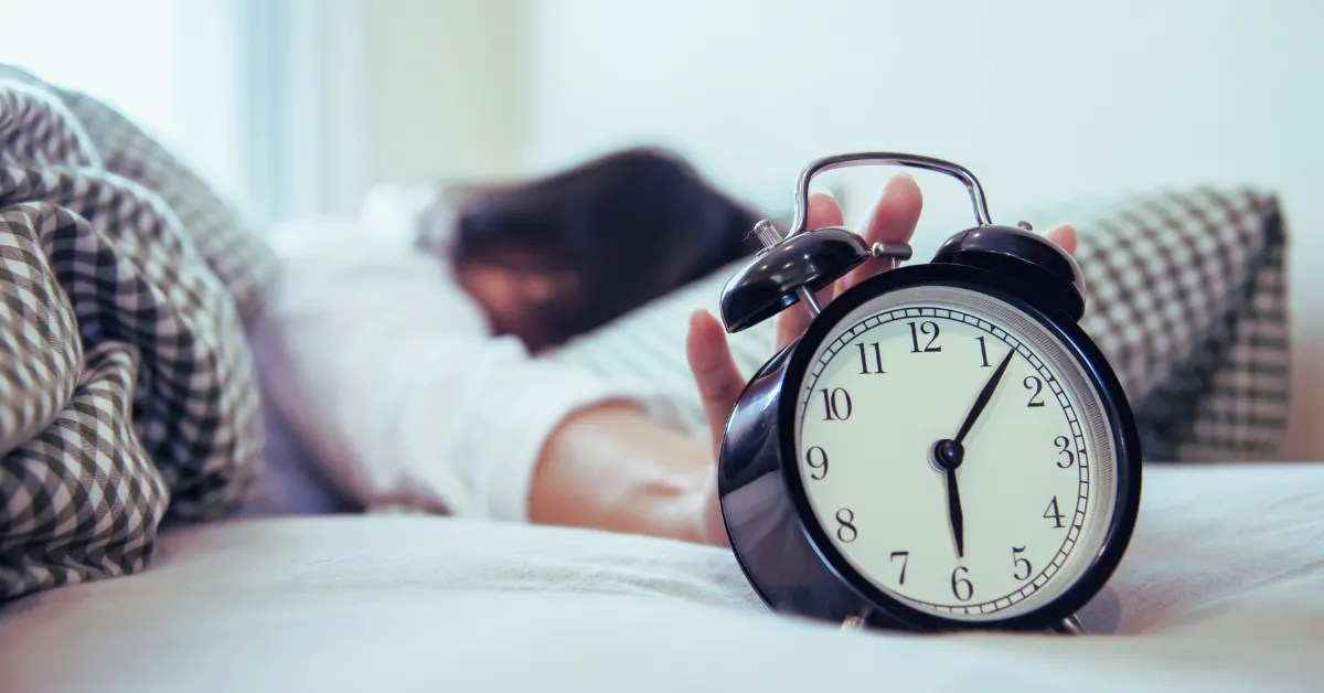 The Amazing 1% Morning Routine for Success in 2025 1 A person reaching out to turn off an alarm clock, symbolizing the start of a productive morning routine for success.