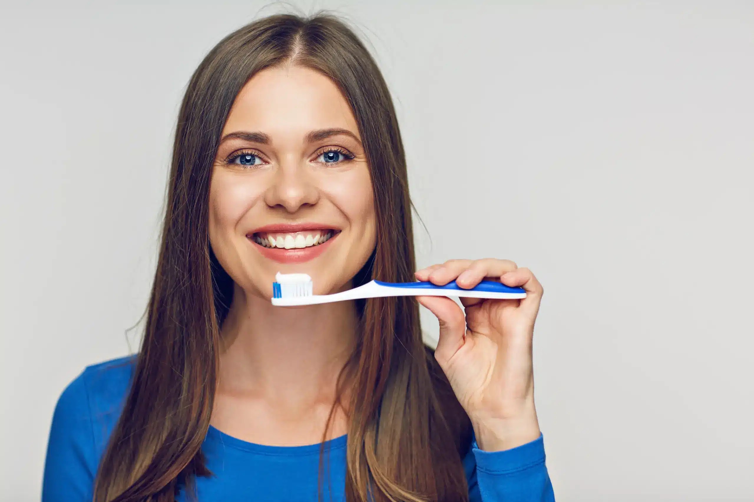 A smiling woman holding a toothbrush, promoting Preventative Dentistry in Thayne at Riverside Dental for healthy smiles
