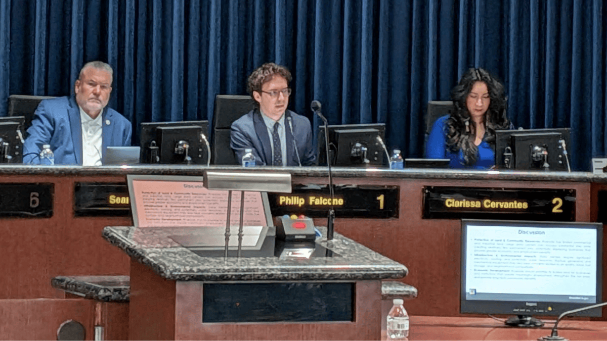 The three council members sit at the dais.
