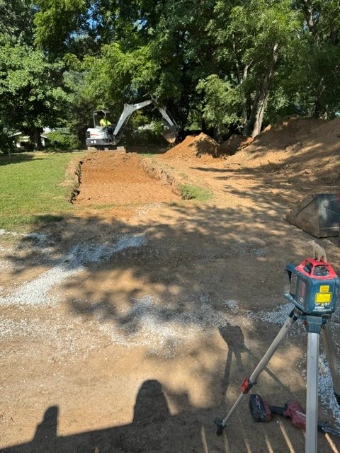 Heavy mini-excavator clearing topsoil and grading land for residential septic tank installation in Bloomington, Indiana.