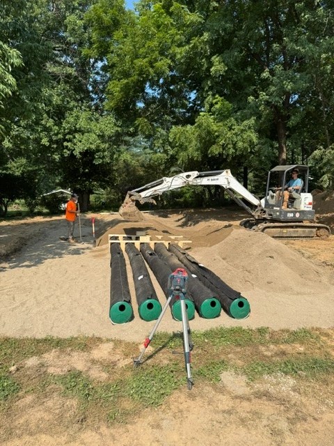 Riverway Plumbing excavation crew assembling perforated drain field distribution pipes and digging absorption trenches.