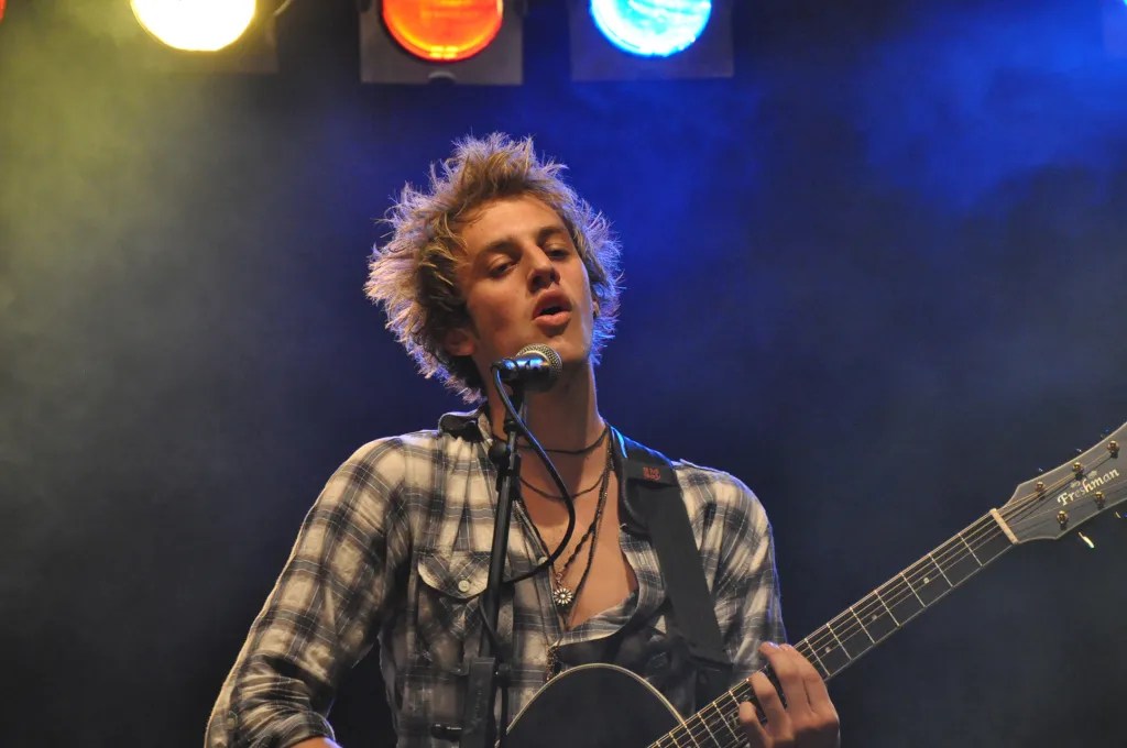 Blonder Singer Songwriter auf Bühne mit Acoustic Gitarre