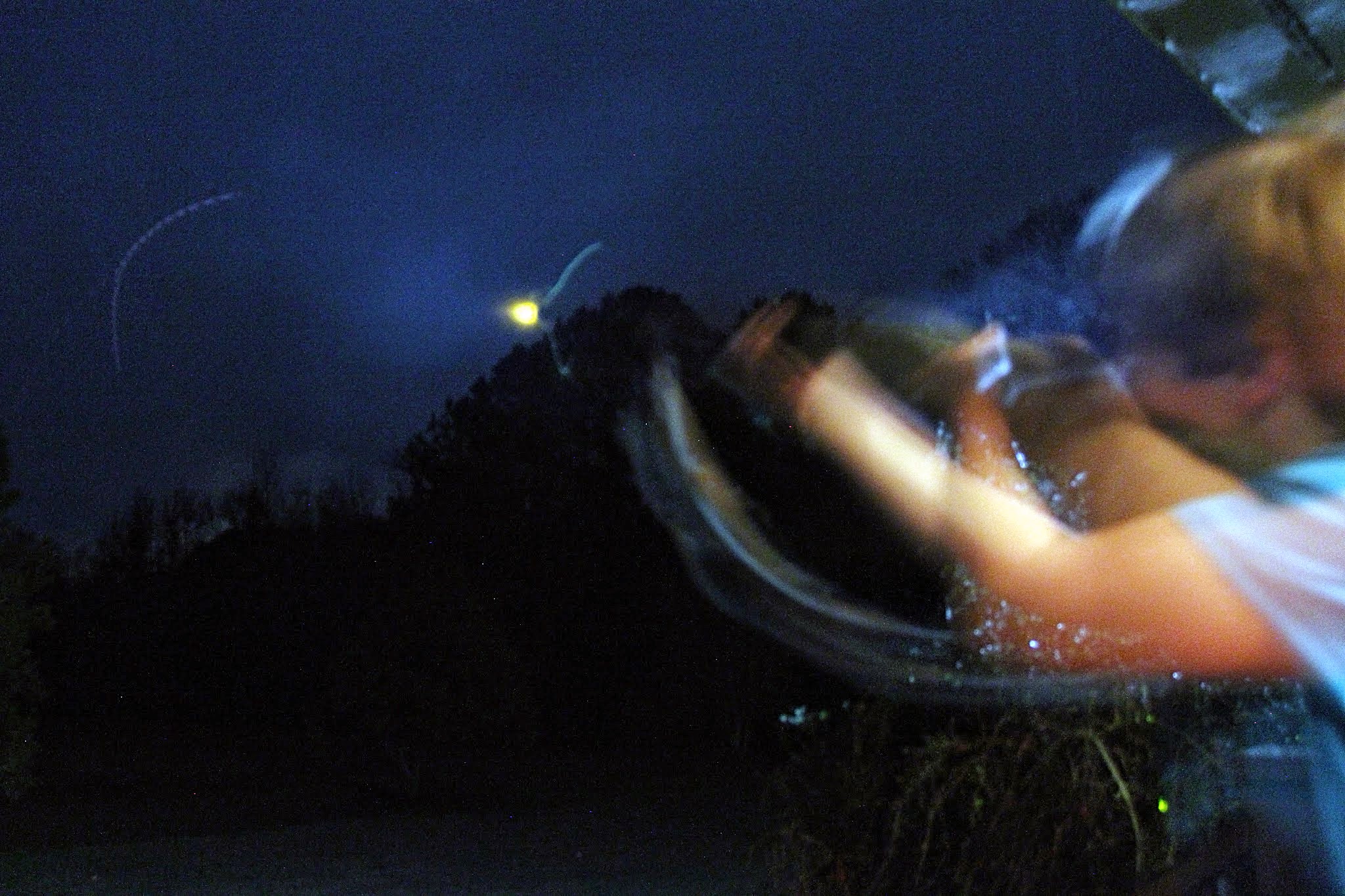 A young boy shoots at skeet in the dark with the aid of glow sticks.