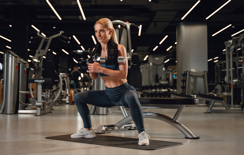 Woman performing squats with the Jacked Ass Belt to build stronger bone density