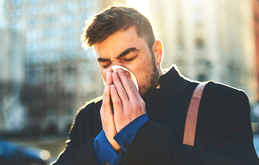 Man sneezing from seasonal allergies in need of a natural essential oil remedy