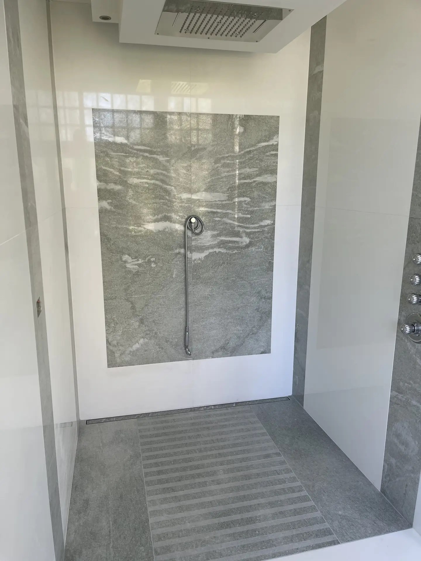 Douche à l’italienne associant un receveur carrelé, du marbre gris et de la céramique blanche