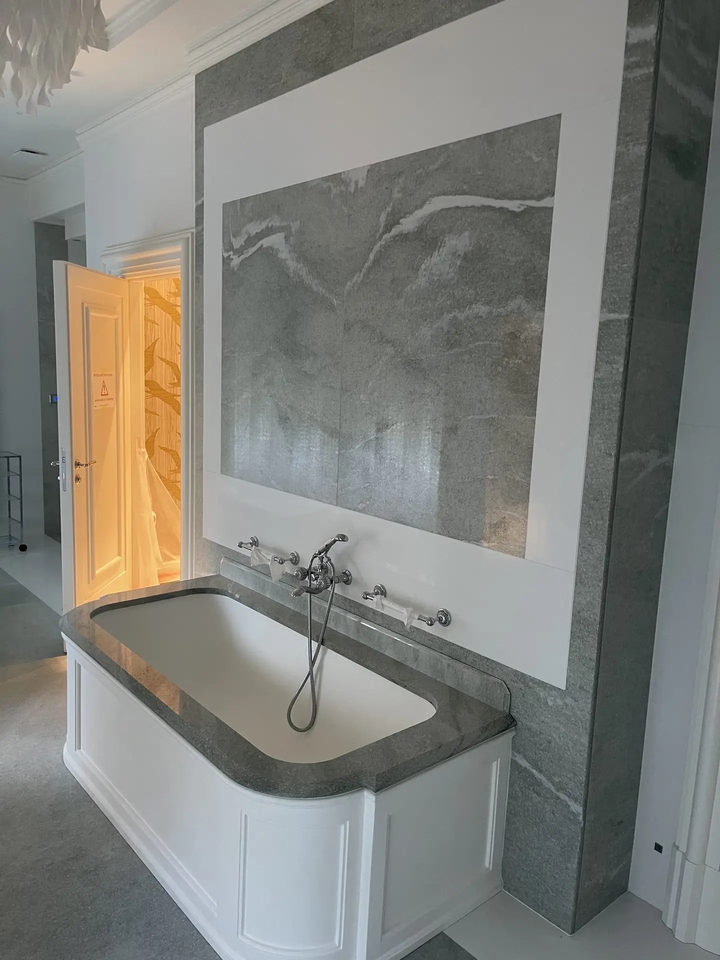 Habillage mural en pierre naturelle grise veinée dans une salle de bain avec baignoire encastrée, réalisation RocaMarbre