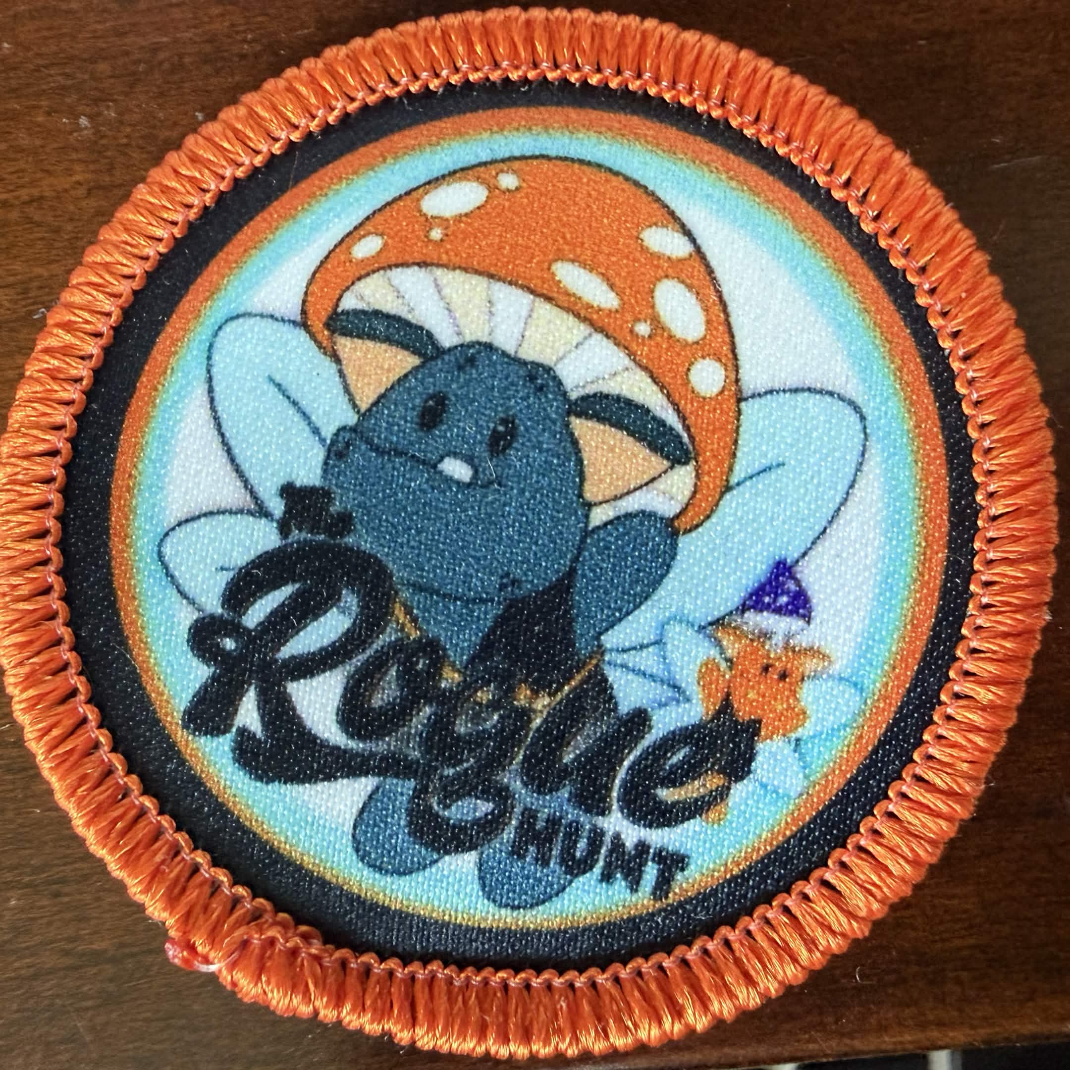 Eugene, the fairy goblin mascot on a light blue background with an orange border. The Rogue Hunt is written across the bottom in black text.