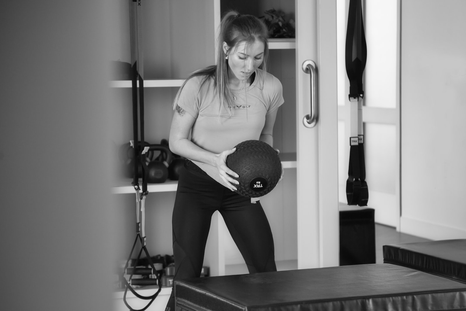 woman in white tank top and black pants sitting on black wooden table