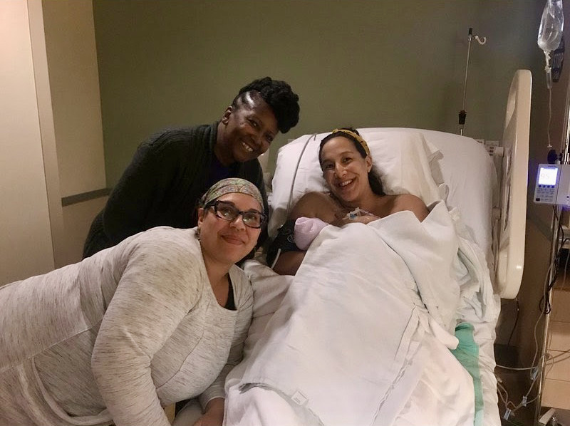 A Rootead doula poses with a client soon after the safe delivery of her baby.