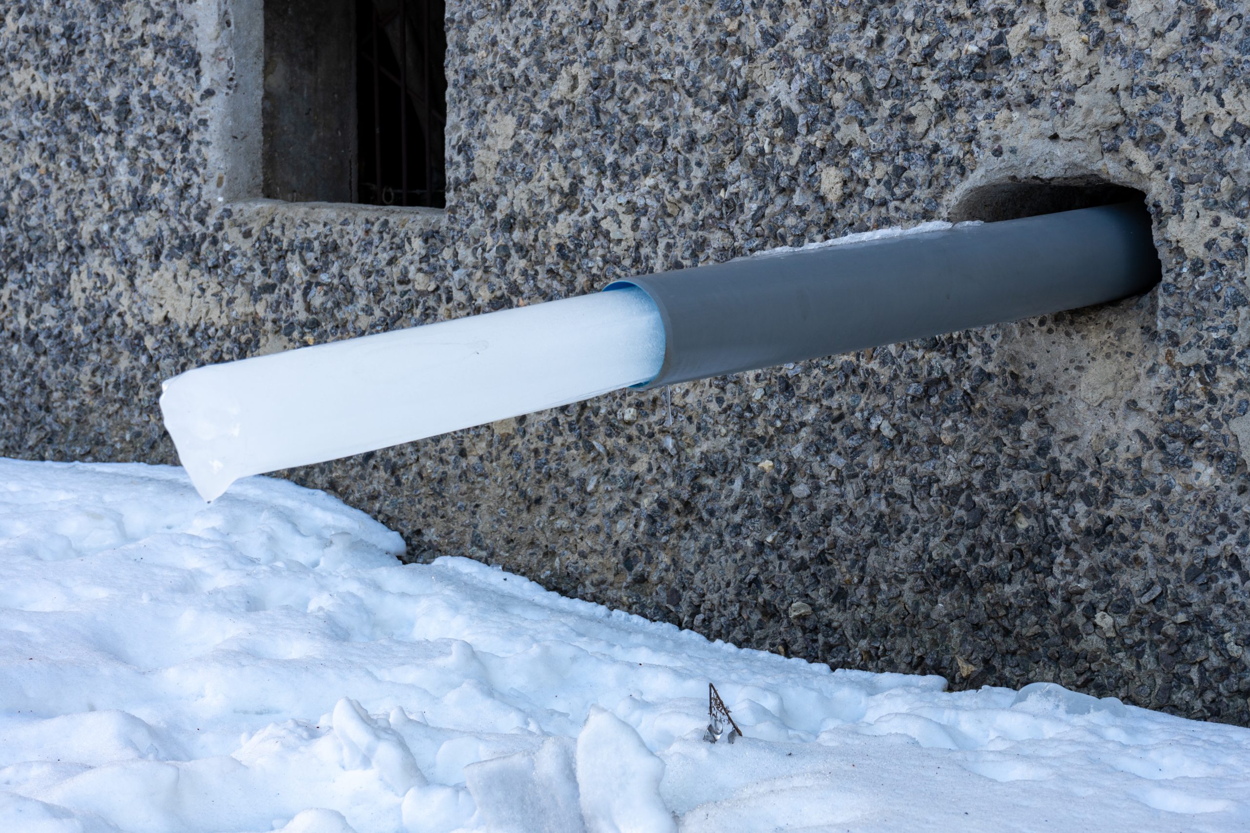 A water pipe in a house with a frozen piece of ice