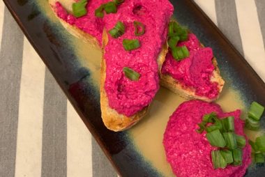 bright pink beet pate is served on two narrow pieces of toast on a blue plate with some green beans