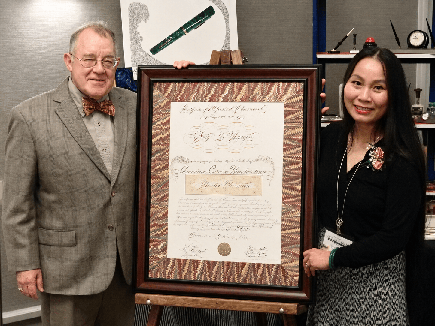 Hong Nguyen receiving Master Penman recognition from Michael R. Sull at the 2021 Ohio Pen Show.