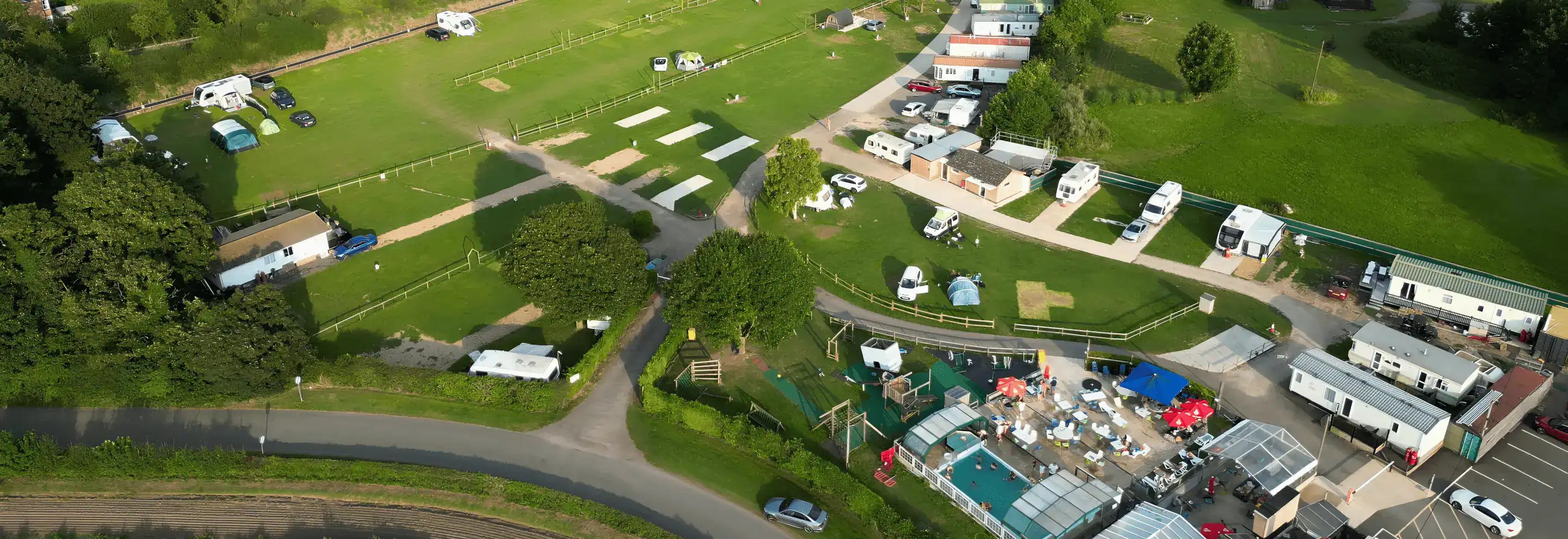 Rose & Crown camping site with caravans, tents, and green fields.