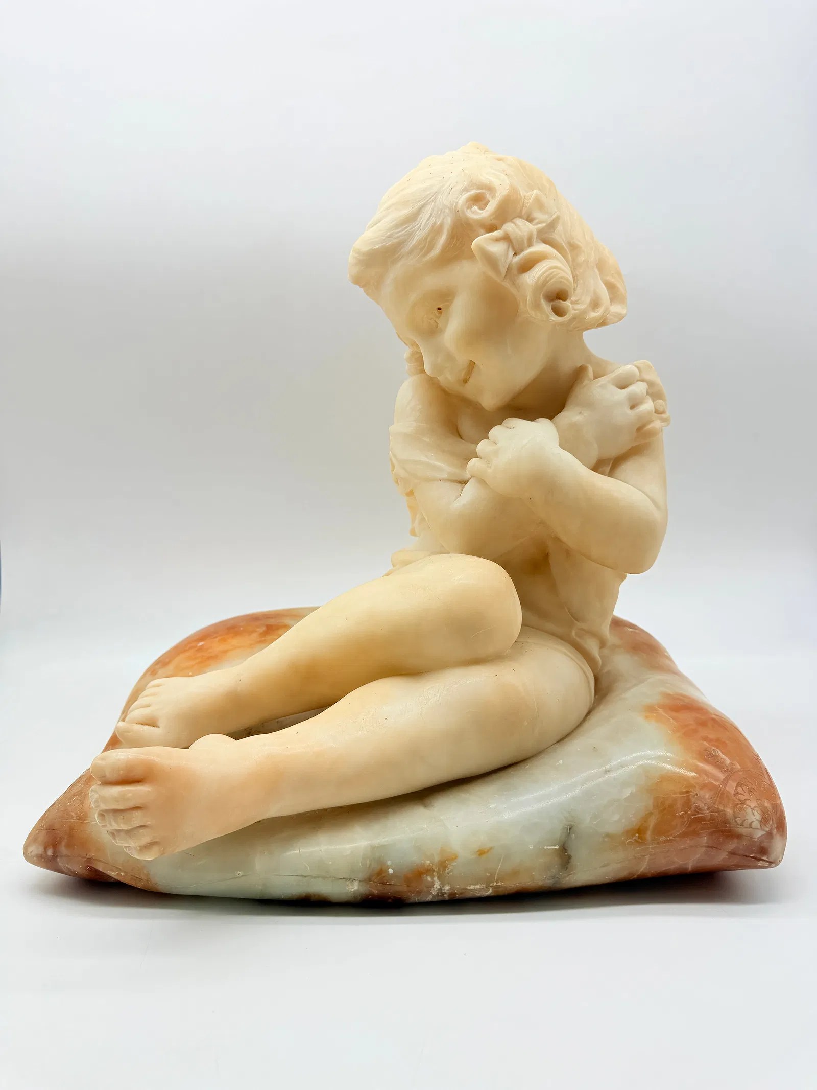 Italian alabaster sculpture of a seated child on a multicoloured marble cushion