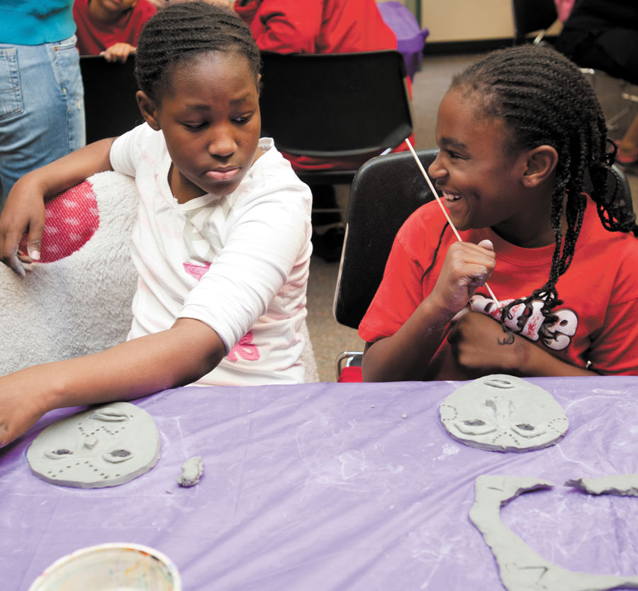 Noel Amie, left, takes a thoughful glance at at clay mask created by a very proud Anglique Amie, right, at the Sandy Springs Library on Feb. 15, part of African American History Month activities.