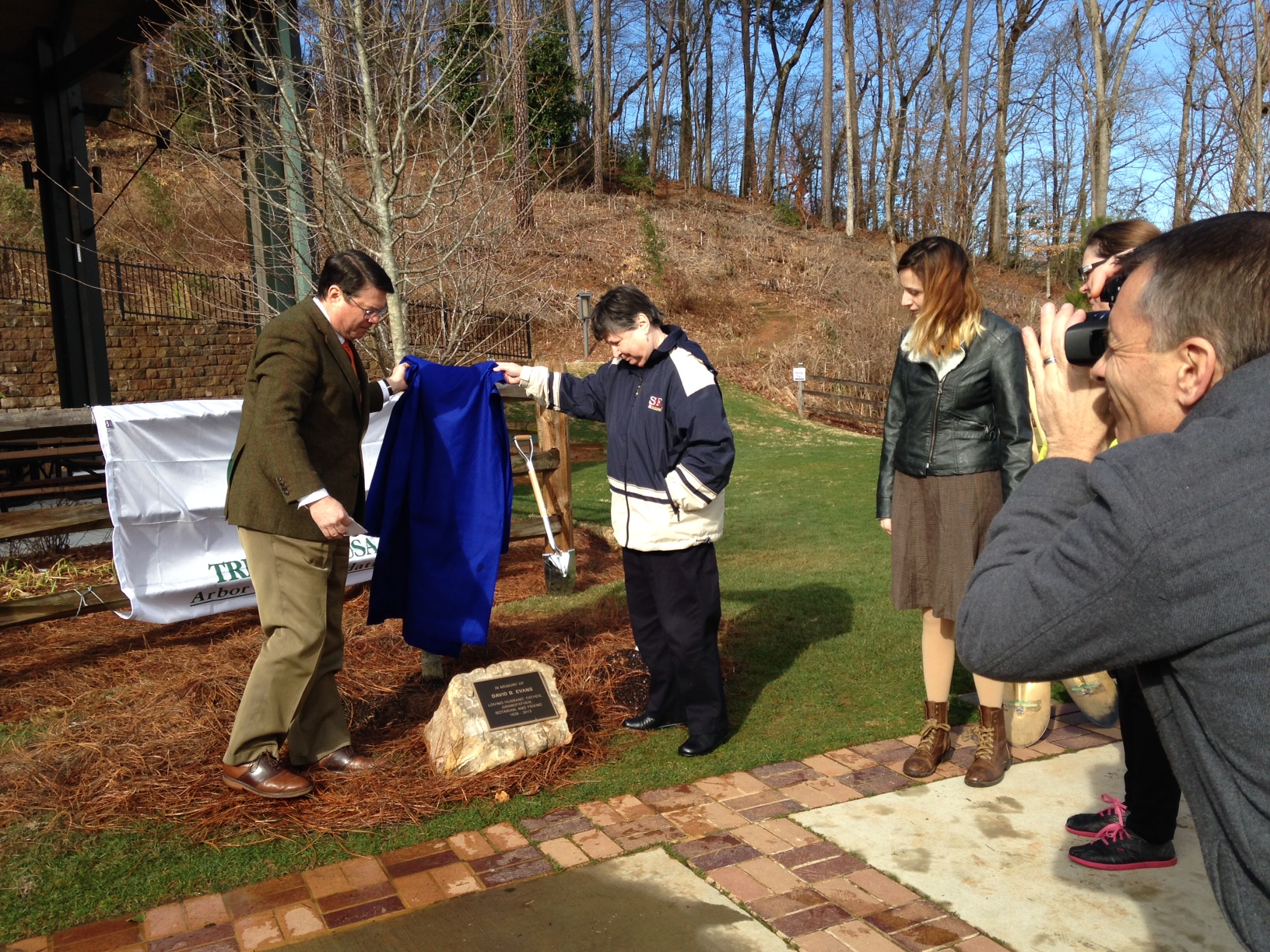 Sandy Springs Mayor Rusty Paul, left, and Barbara Evans unveil a plaque at the foot of a tree planted in memory of Mrs, Evans' husband, Dave Evans, during an Arbor Day celebration Feb. 21 at Morgan Falls Overlook Park.