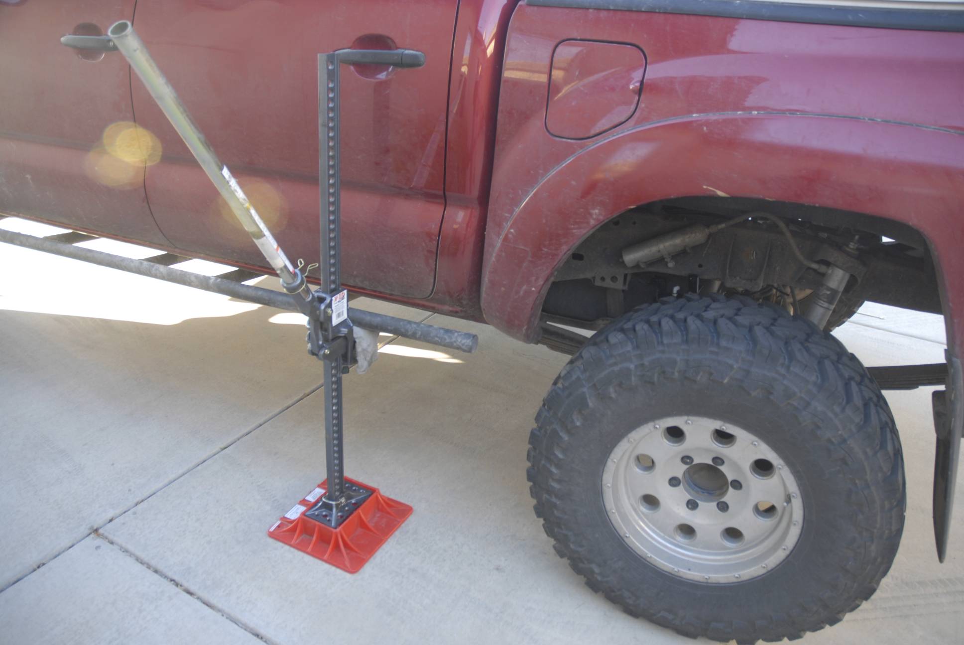 Hi Lift time. We were able to jack the frame up using the sliders high enough that I could slide the assembly in without taking off the rear wheel. With the spare out, there's more than enough space to maneuver under the vehicle.