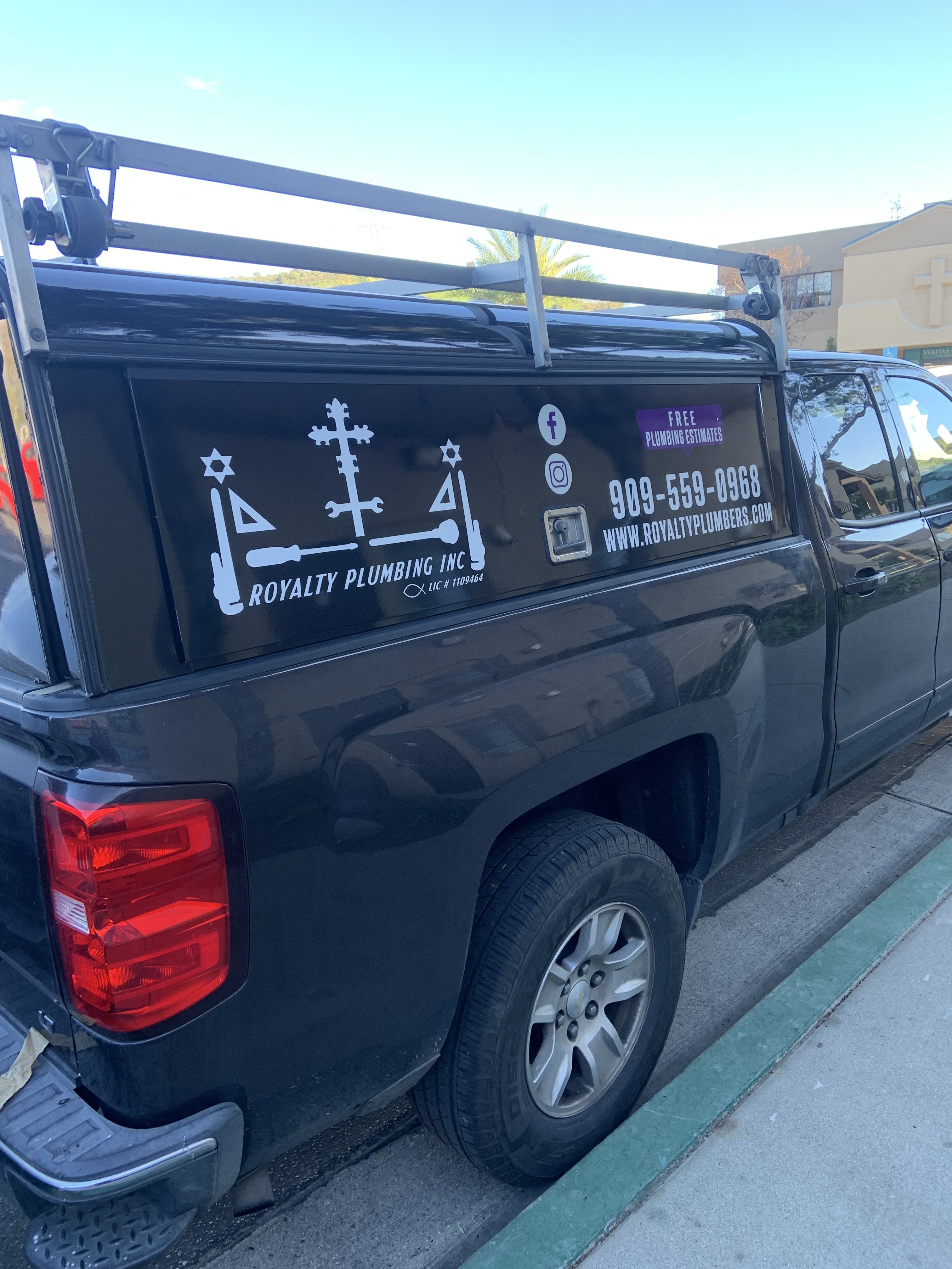 Royalty Plumbers branded service truck with ladder rack and utility shell parked at a customer's home