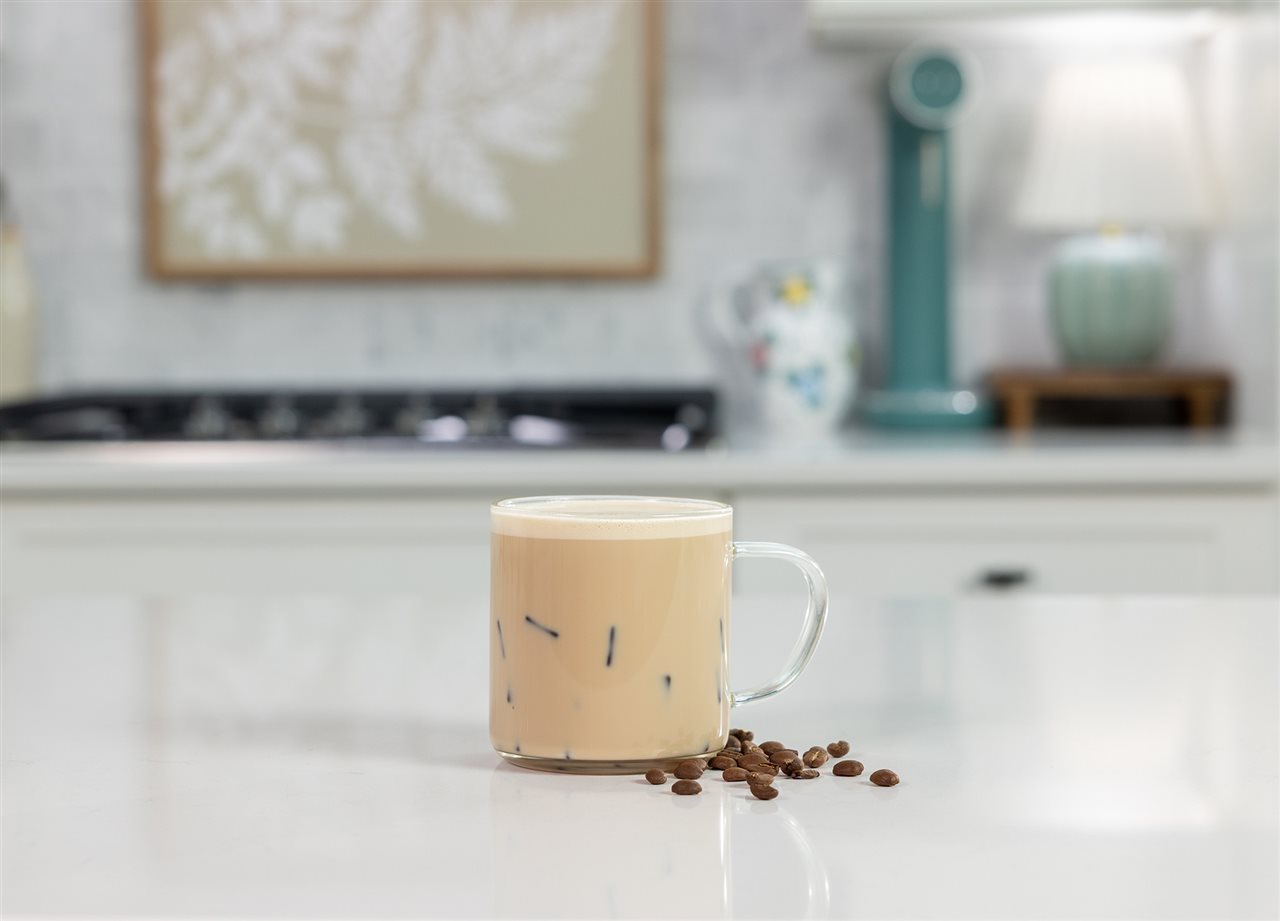 A cup of Organic Valley Coffee Sparking Milk with coffee beans sprinkled around the base.