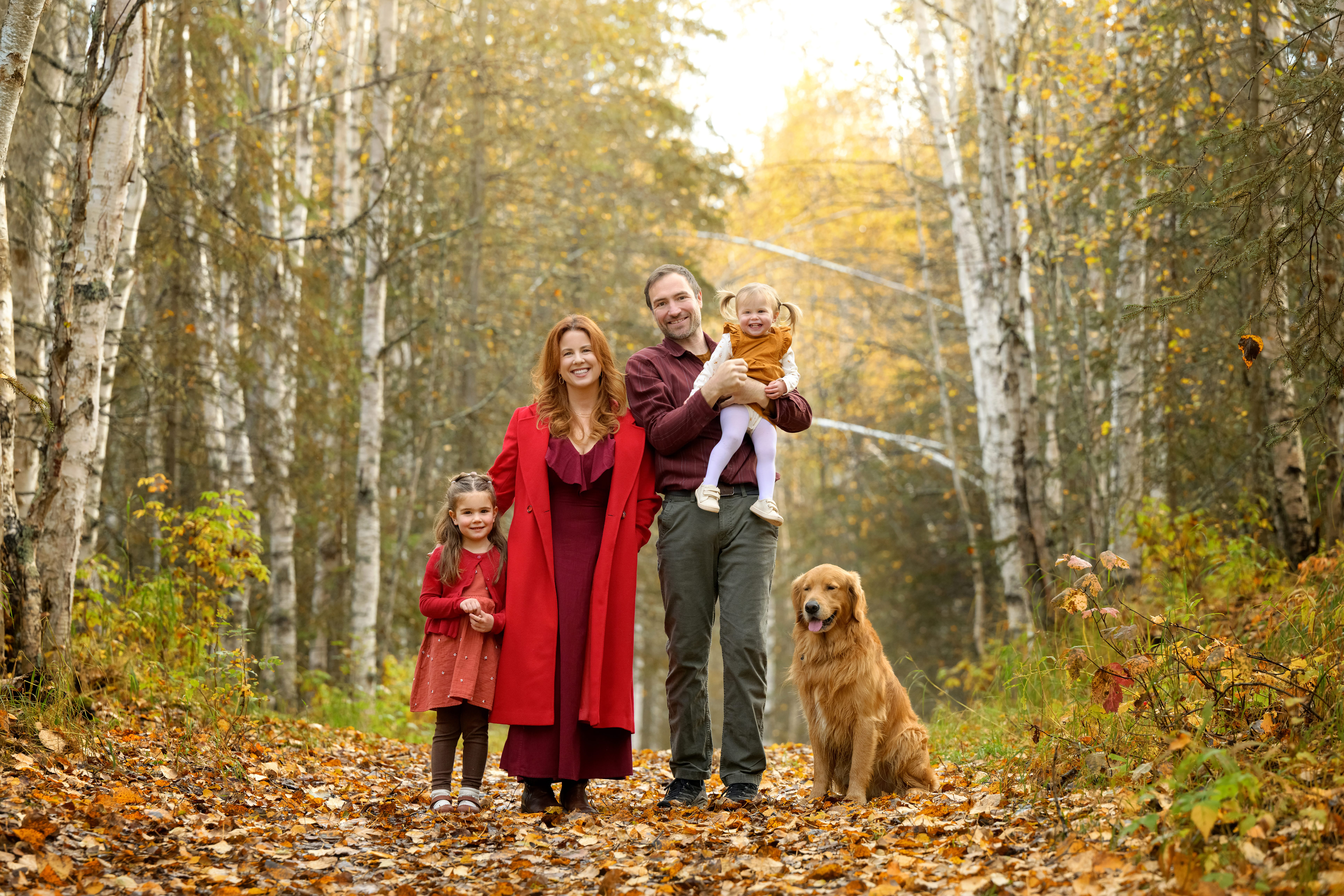 Ruby Jones with her husband, two daughters, and golden retriever in a birch forest