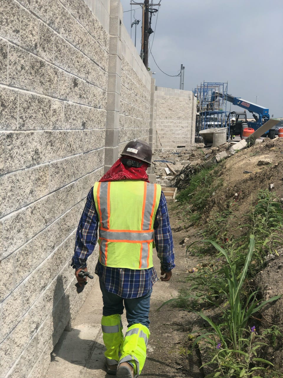 Rucomaya team member walking next to a completed concrete contractor masonry project wall.