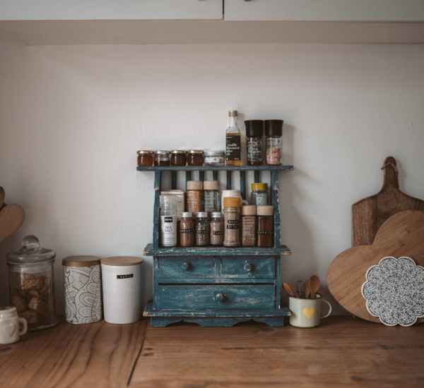 Rustic wooden countertop with neatly organized spice rack in home kitchen.