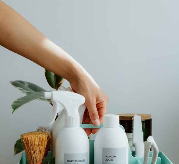 Hand arranging cleaning products in a tidy organizer, promoting cleanliness and order.