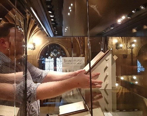 M. Furness positioning mounted book in the case.
