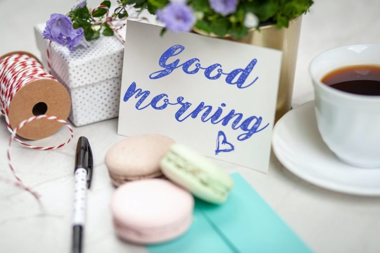 filled teacup with saucer beside good morning card and pen and macaroons benefits of a slower morning routine slow morning