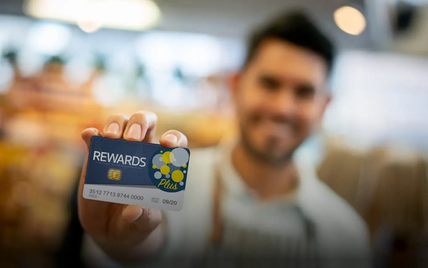 Customer holding a rewards card for a customer loyalty programs offering discounts and incentives.