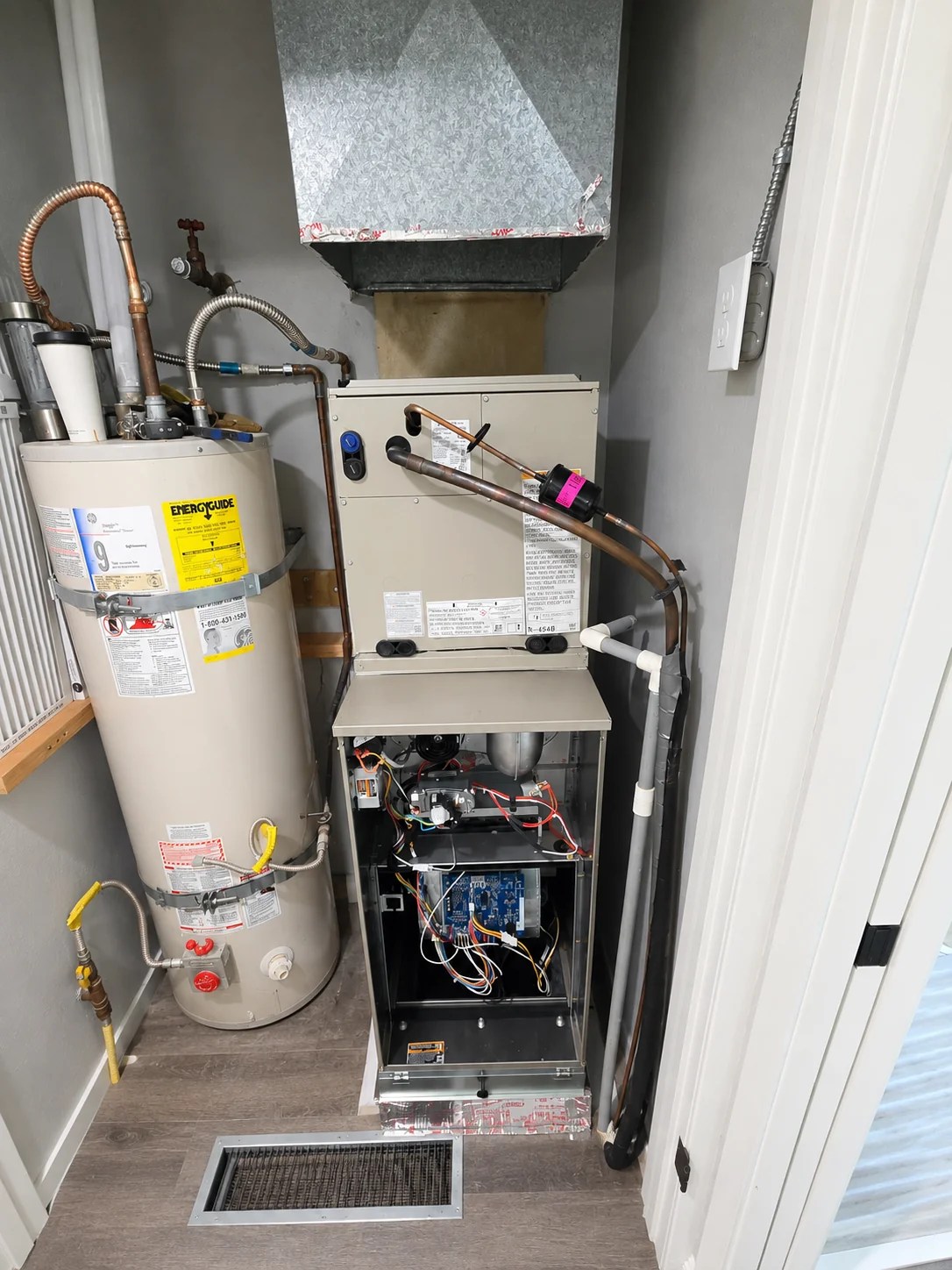 Residential furnace with exposed controls installed beside a water heater