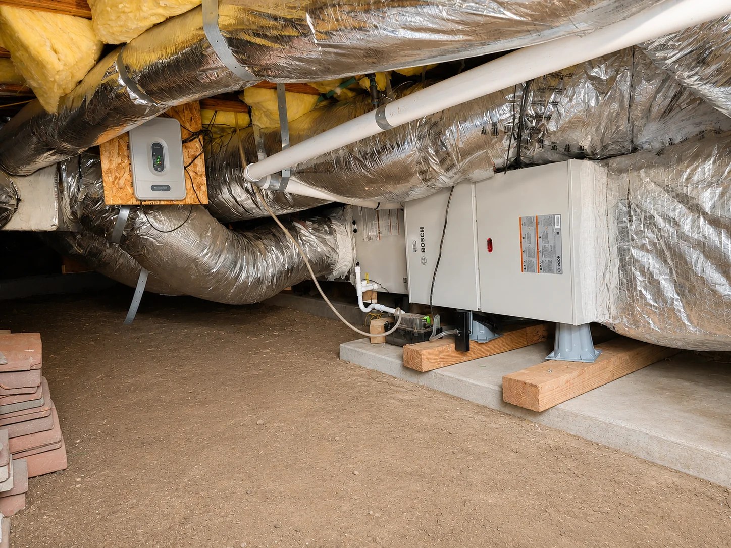 Bosch HVAC air handler connected to insulated ductwork in a crawl space