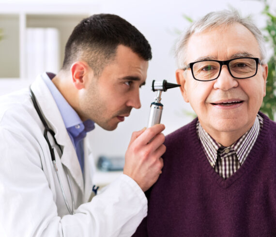 Doctor holding otoscope and examining patient ear Doctor holding otoscope and examining patient ear