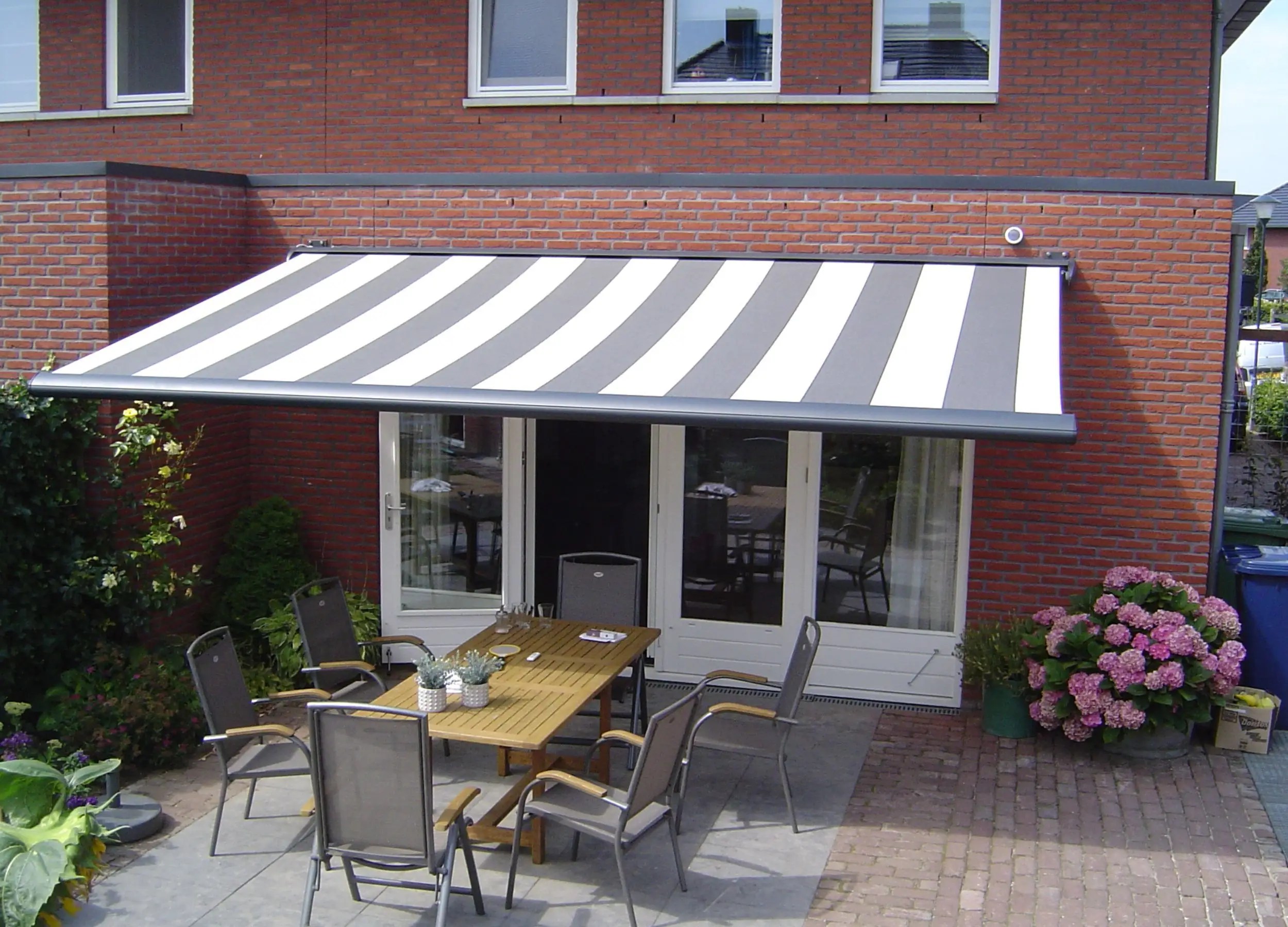 Saffron Signature Quendon awning with grey and white striped fabric extended over patio doors.