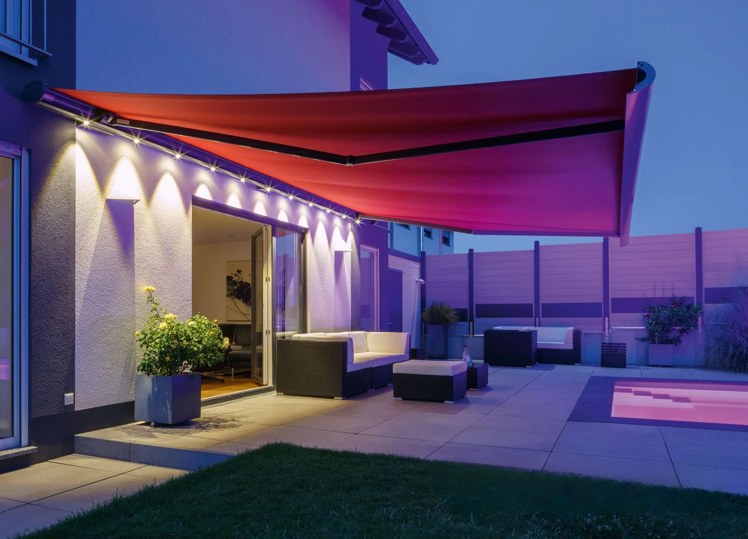 Weinor Opal awning extended over a patio at night with integrated LED lights illuminating the space.