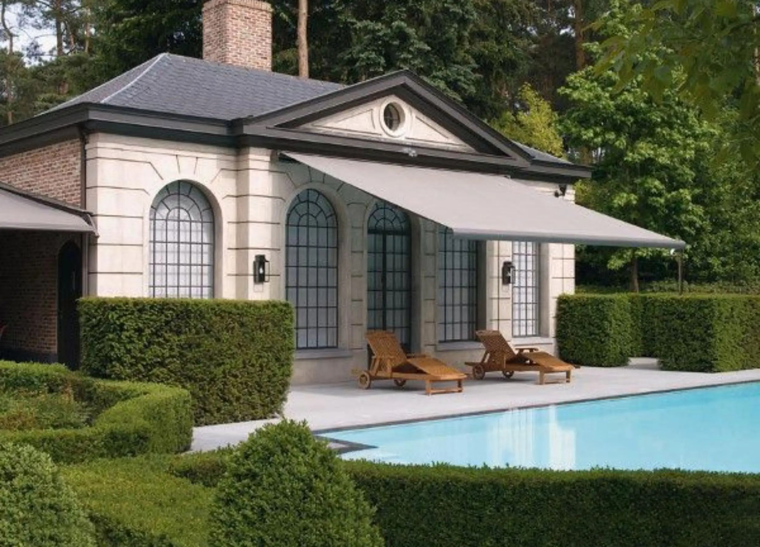 Weinor Opal awning extended over a poolside terrace with sun loungers, mounted on a traditional-style