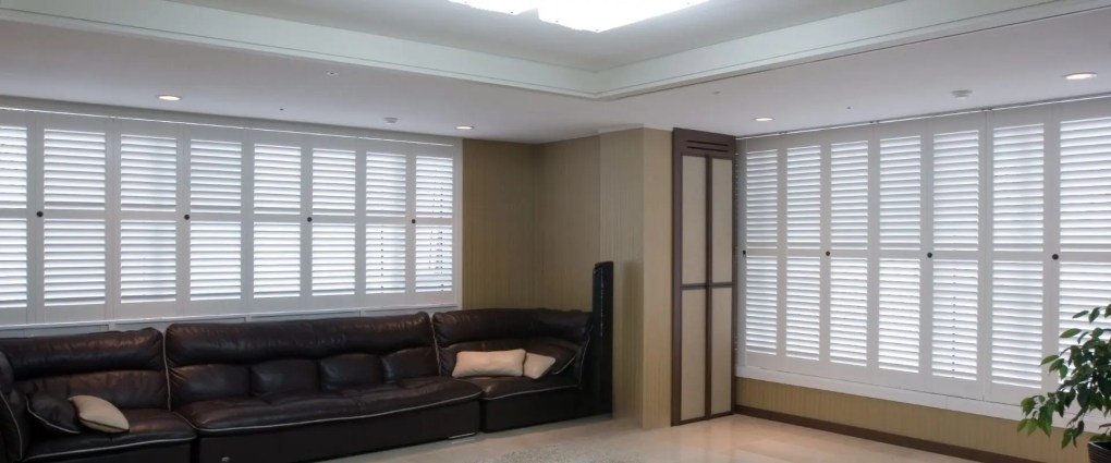 White plantation shutters installed across large living room windows