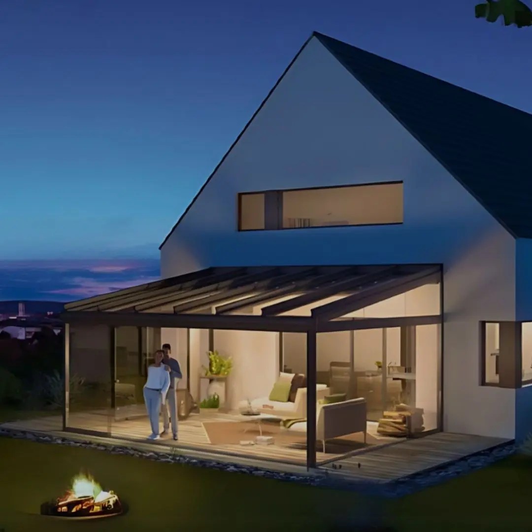 Glass veranda at dusk with warm interior lighting and outdoor fire pit
