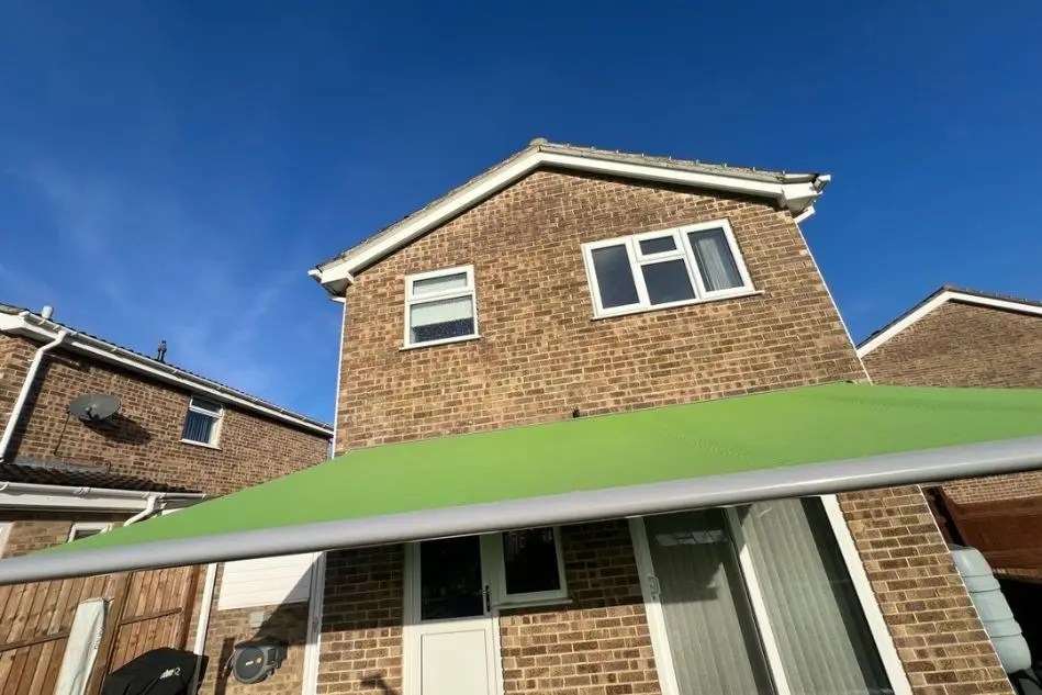 Fully extended green patio awning covering outdoor seating area