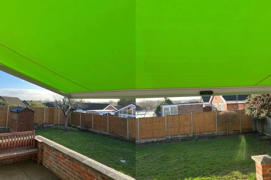 A fully extended green patio awning providing generous shade across the garden seating area, ideal for sun protection and outdoor relaxation.